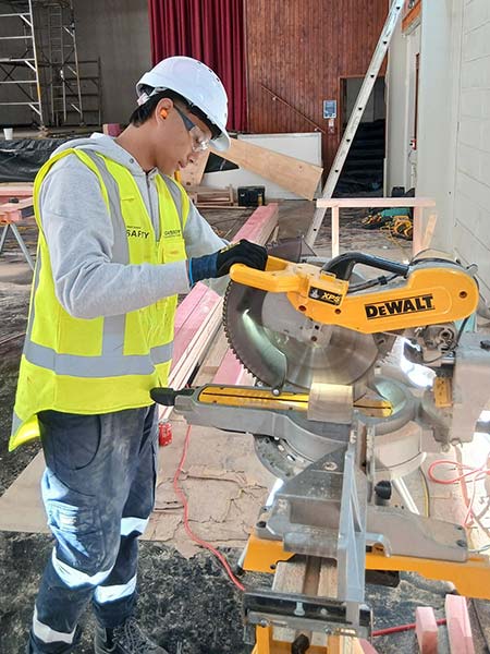 MAGS Gateway Student Kobe using compound mitre saw on Cassidy Construction site